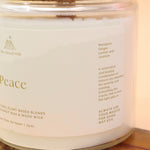 An up-close image of the Peace Intention Candle on an agate slice all on a pink and yellow background.