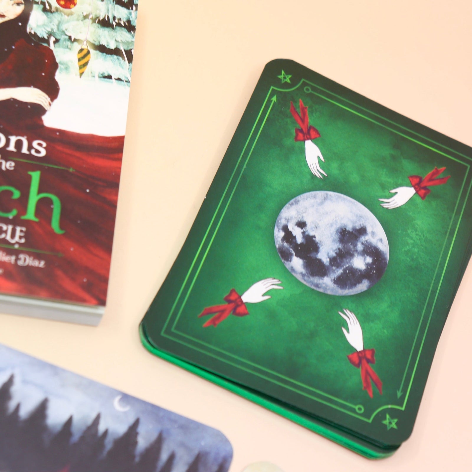 The contents of the Seasons of the Witch Yule Oracle Card Deck on a pink and yellow background.