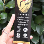 An up-close image of someone holding the Krampus Premium Incense in front of a green bush.