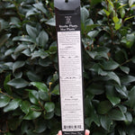 Someone holding the Krampus Premium Incense in front of a green bush, showing off the back