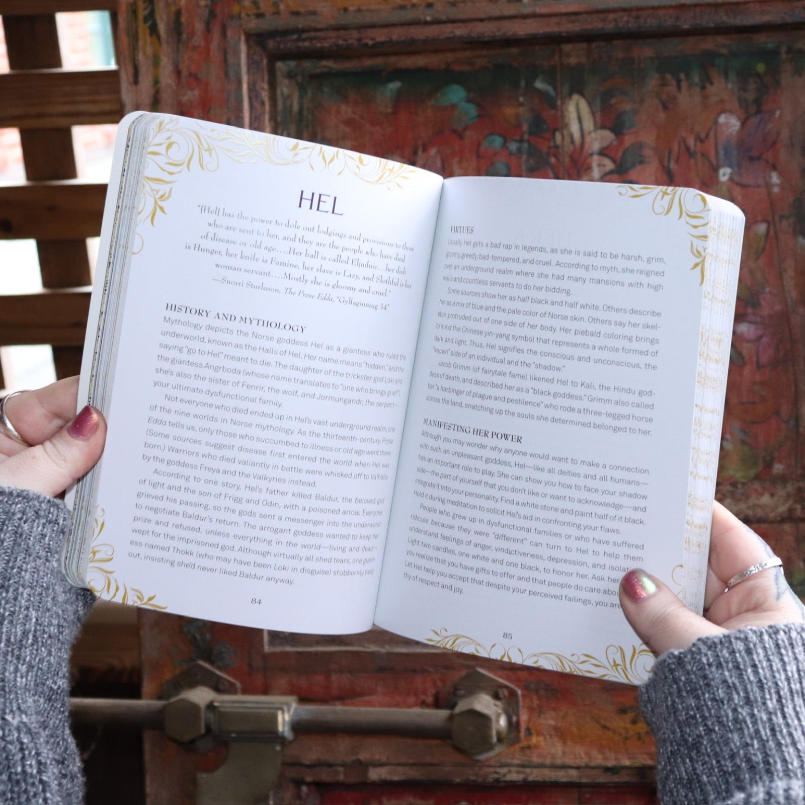 Someone holding the Find Your Goddess Paperback Book open in front of a wood background, showing off some pages.