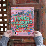 Someone holding the 1990s Coloring Book in front of a wooden background. 
