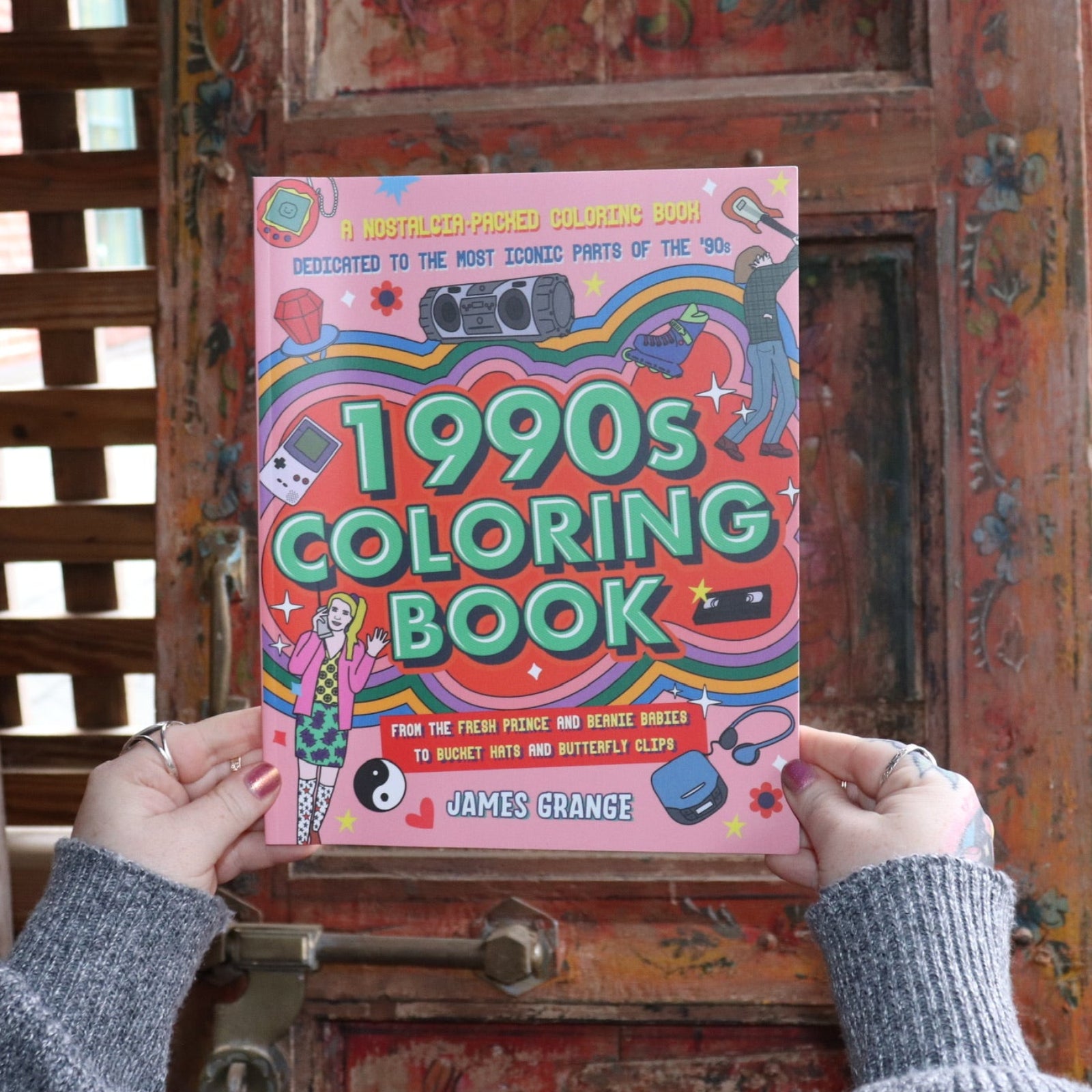 Someone holding the 1990s Coloring Book in front of a wooden background. 