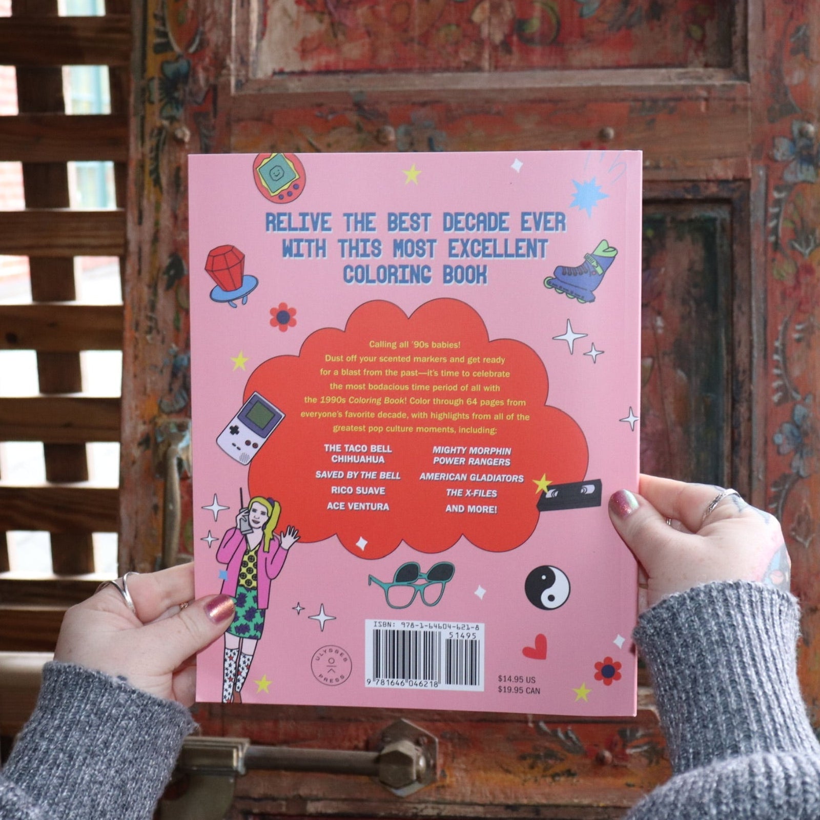 Someone holding the 1990s Coloring Book in front of a wooden background, showing off the back.