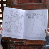 Someone holding the 1990s Coloring Book open in front of a wooden background, showing off the pages.
