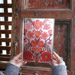 Someone holding the Love Oracle Foiled Hardcover Journal in front of a wooden background.