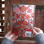 Someone holding the Love Oracle Foiled Hardcover Journal in front of a wooden background, showing the back.