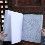 Someone holding the Golden Girls Color-by-Number Coloring Book open in front of a wooden background, showing off the pages.