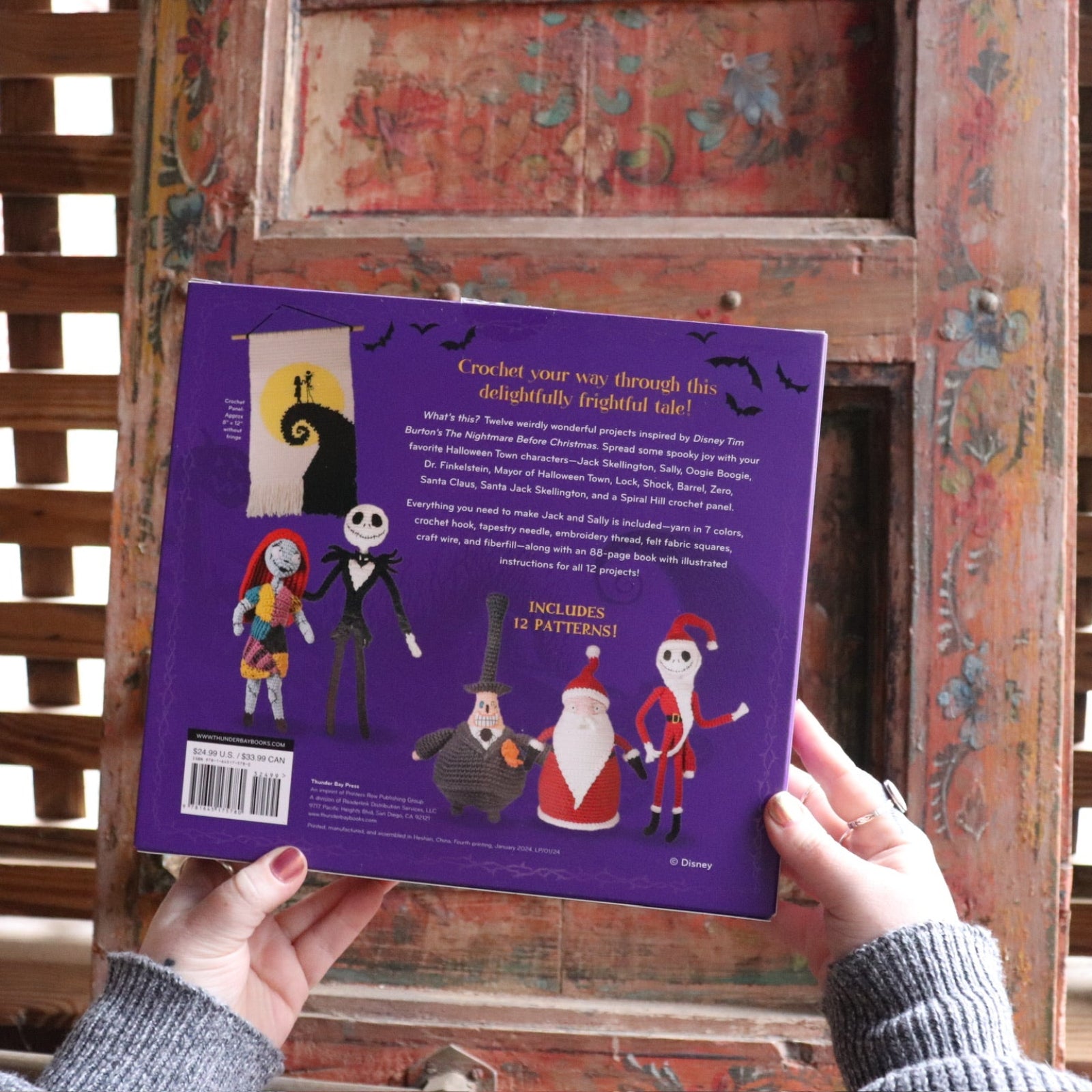 Someone holding the The Nightmare Before Christmas Inspired Crochet Kit in front of a wooden background, showing off the back.