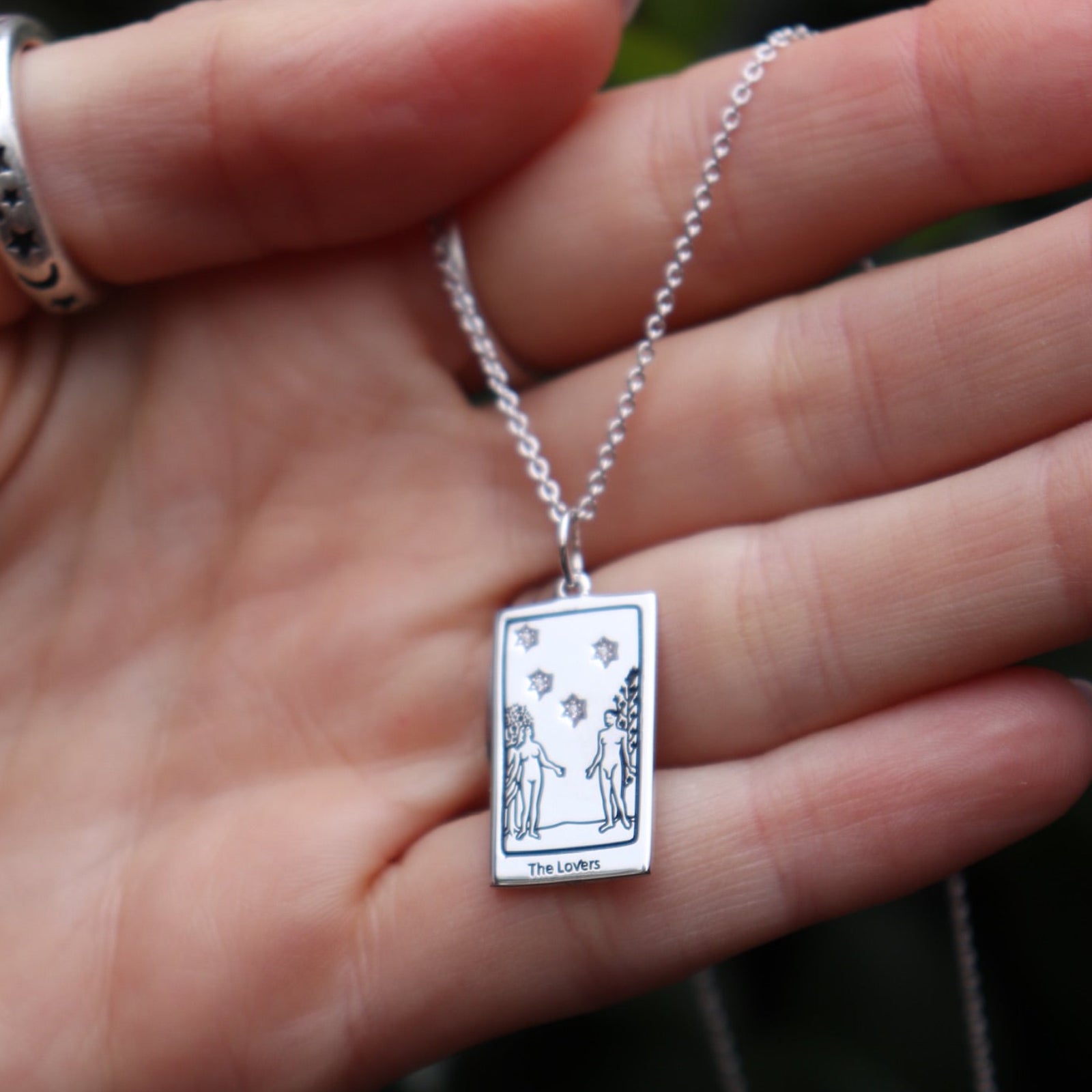 Someone holding the The Lovers Tarot Sterling Silver Necklace.