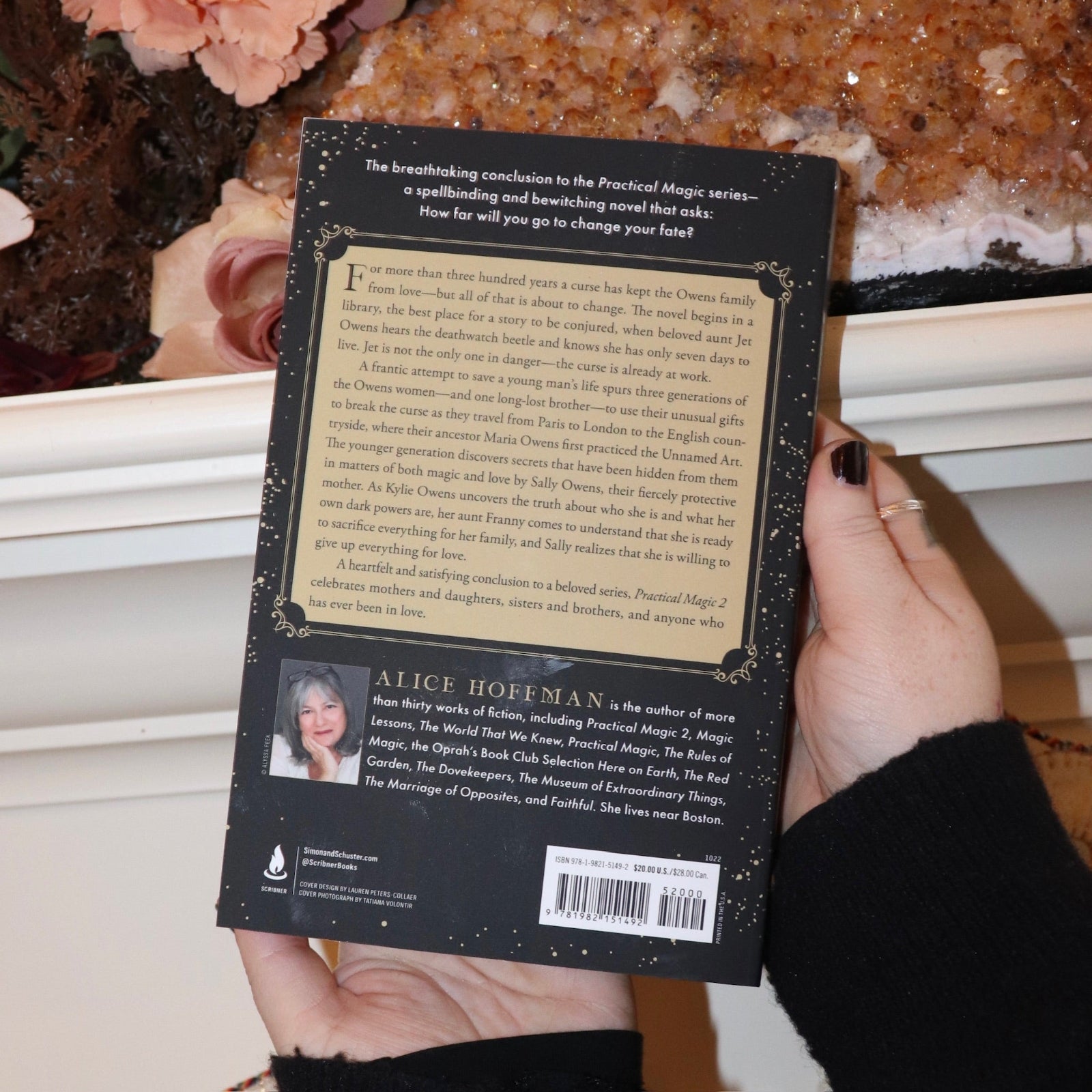 Someone holding the Practical Magic 2 Book of Magic in front of a white background with a large citrine piece, showing off the background.