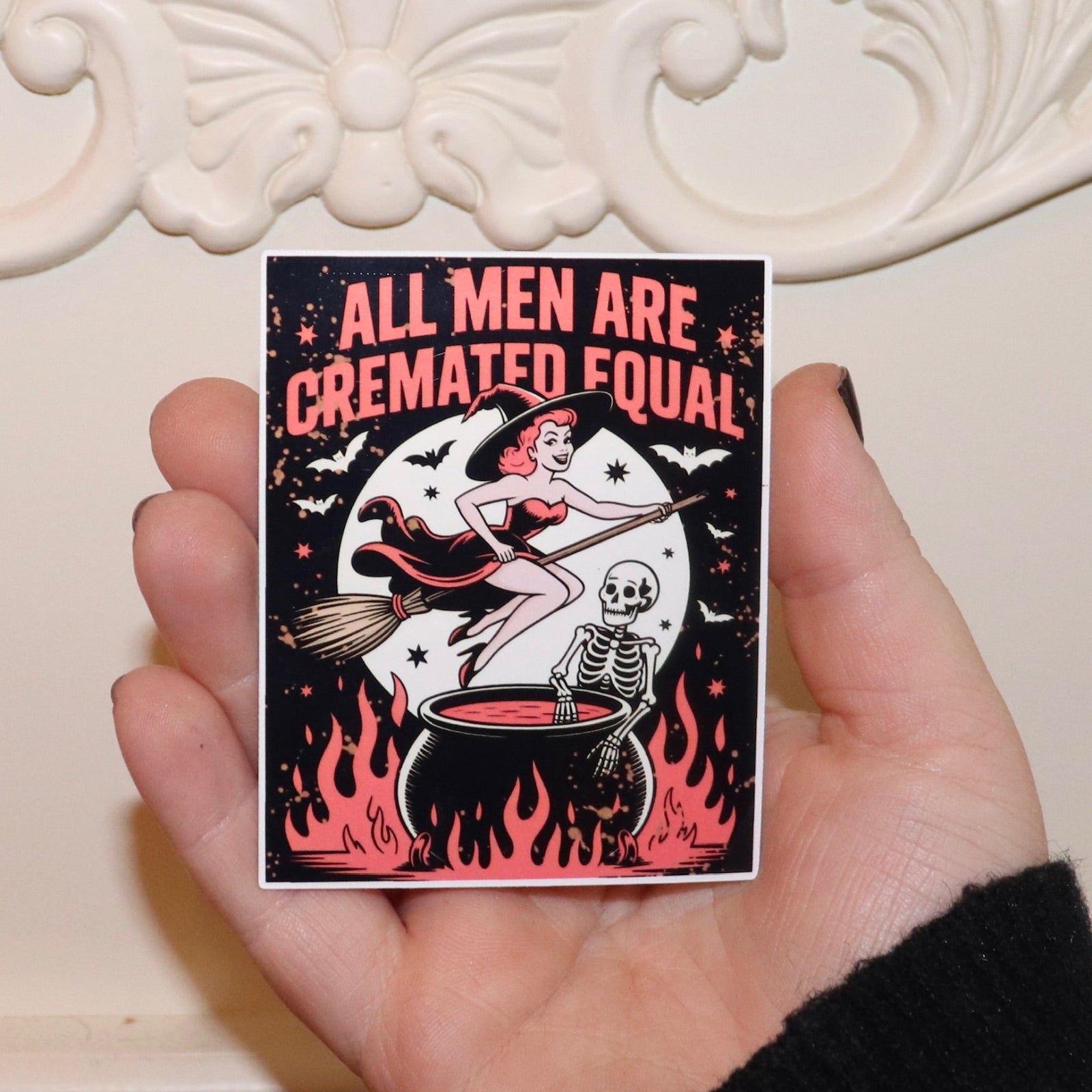 Someone holding the All Men Are Cremated Equal Sticker in front of a white background.