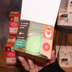 Someone holding the Geometric Santa Bath Bomb in front of other bath bombs with the top open, showing off the bath bomb.