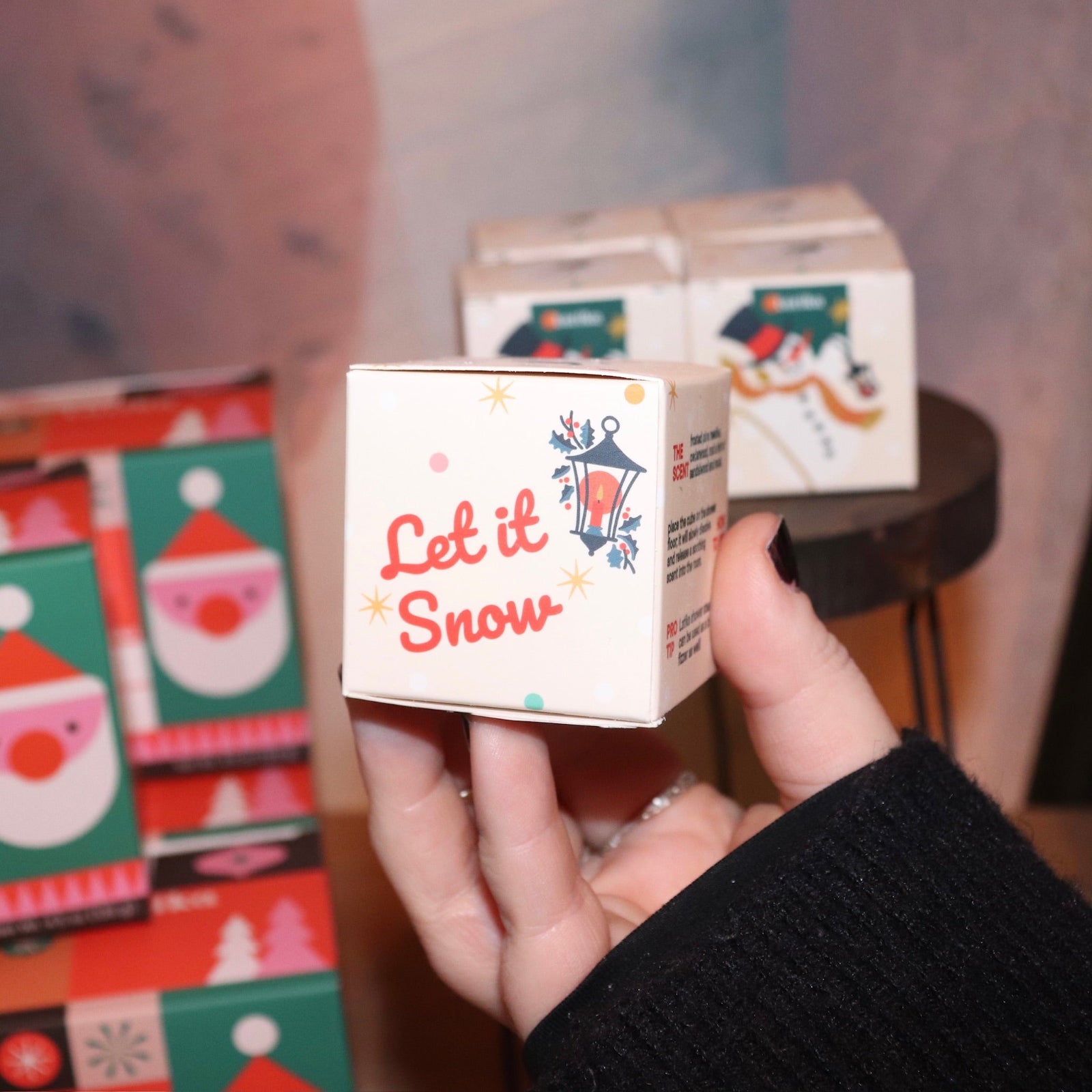 Someone holding the Snow Shower Steamer in front of other shower steamers, showing off the side.