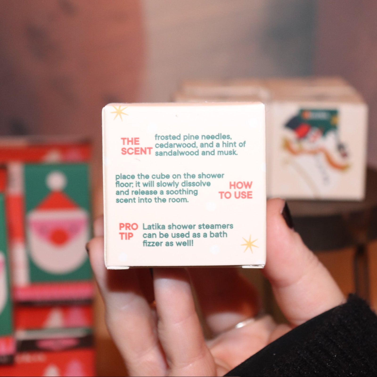 Someone holding the Snow Shower Steamer in front of other shower steamers, showing off the back.