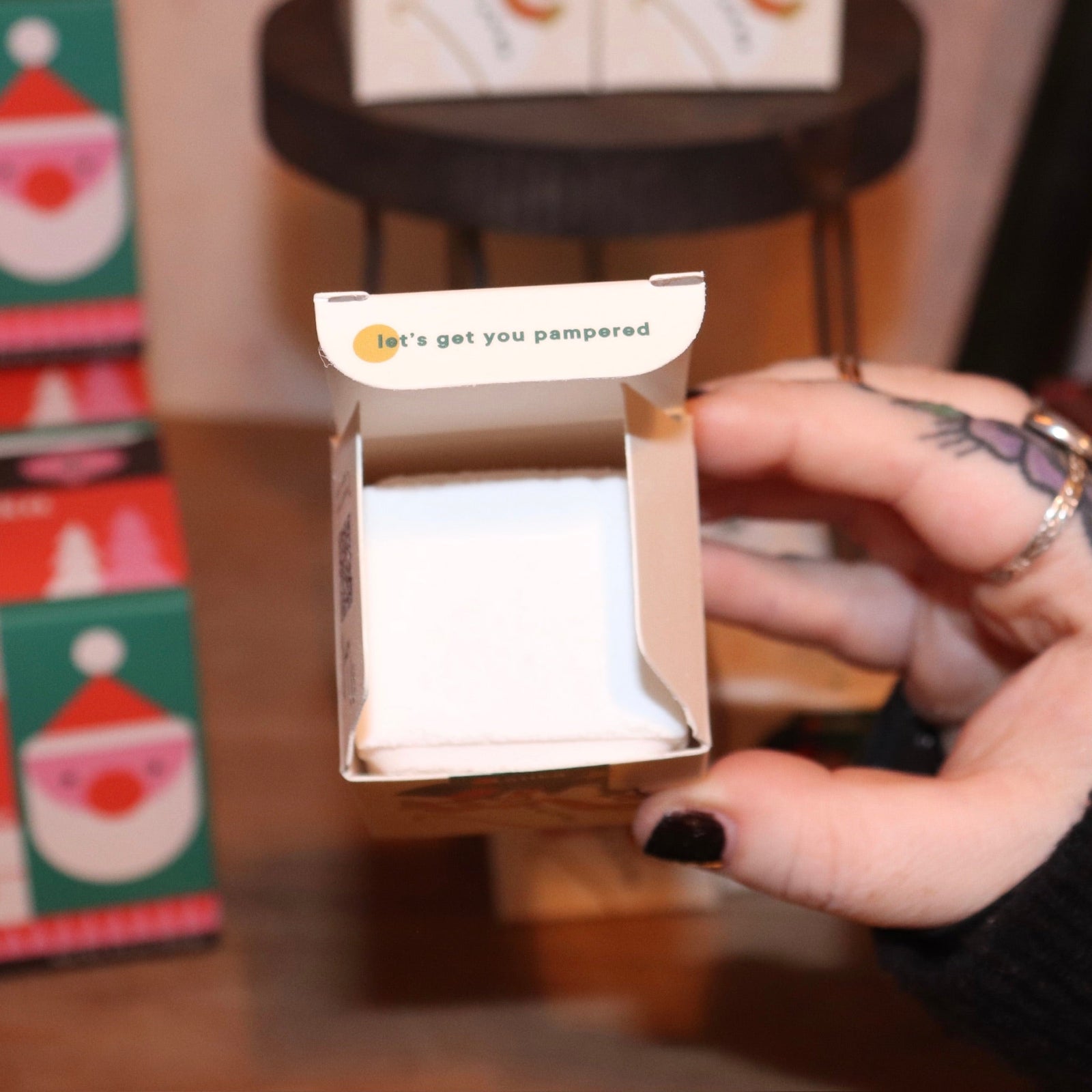 Someone holding the Snow Shower Steamer in front of other shower steamers, with the lid open showing off the inside.