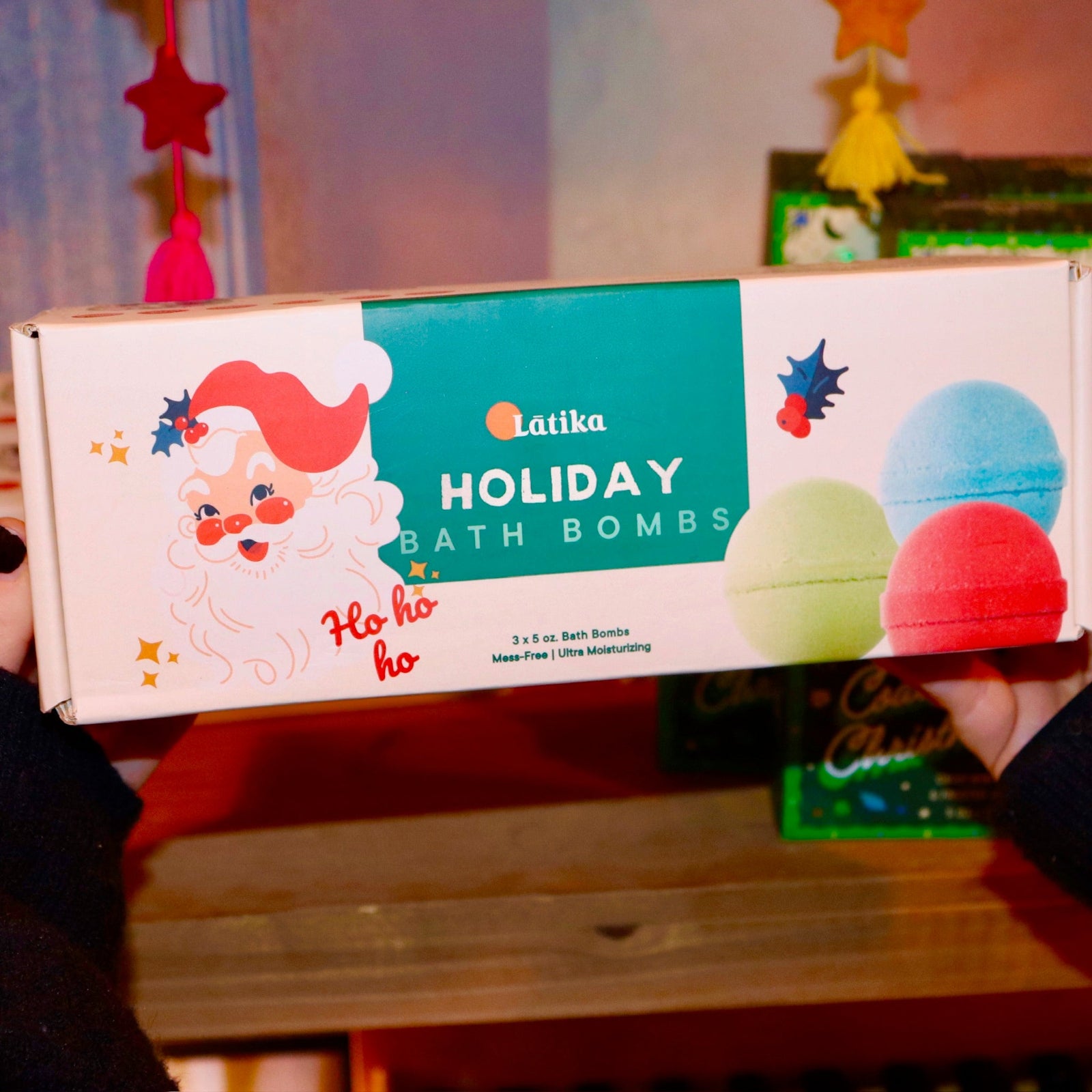Someone holding the Holiday Christmas Bath Bomb Set in front of a colorful background.