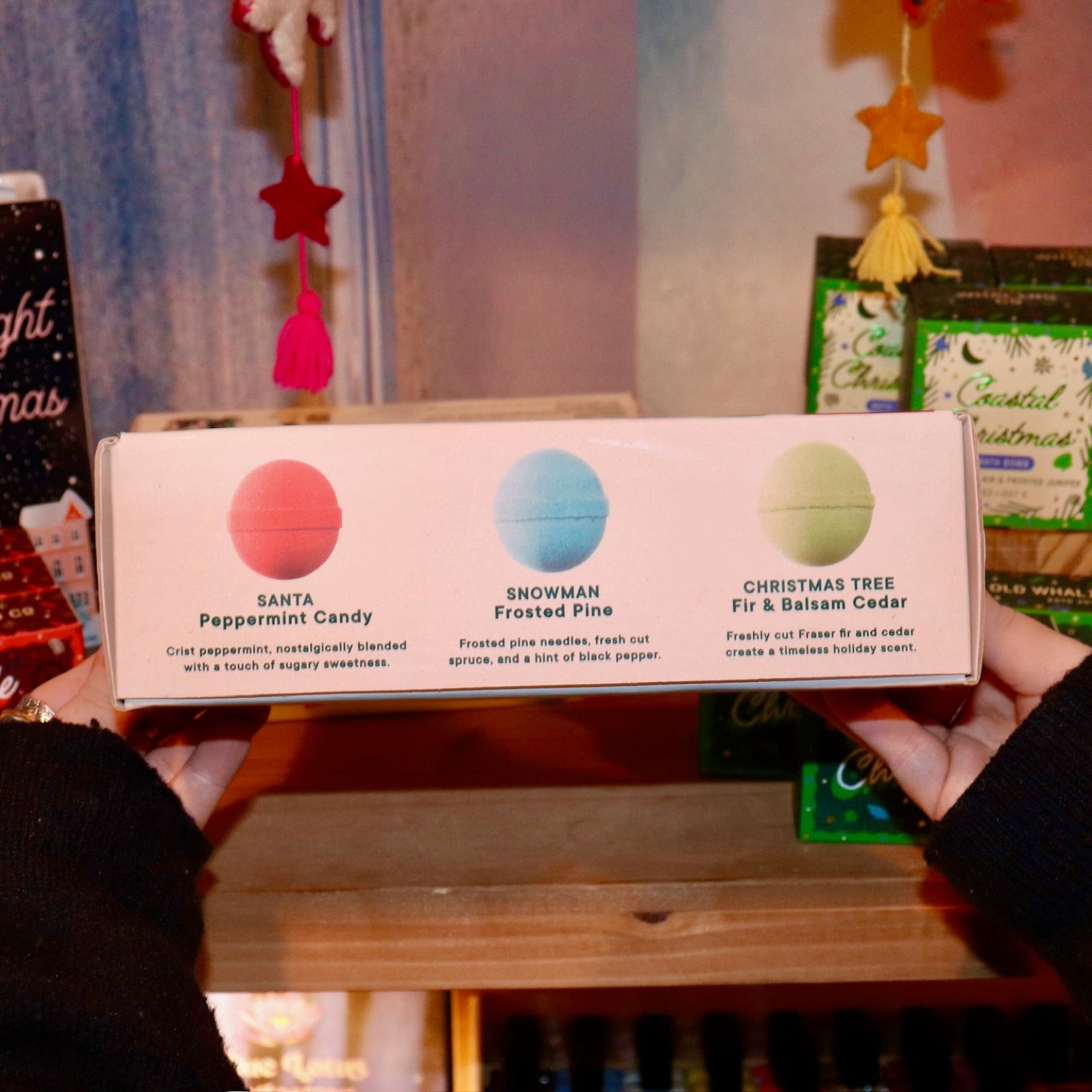 Someone holding the Holiday Christmas Bath Bomb Set in front of a colorful background, showing off the back.