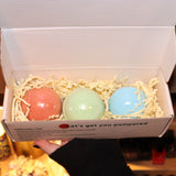 Someone holding the Holiday Christmas Bath Bomb Set in front of a colorful background, showing the inside.