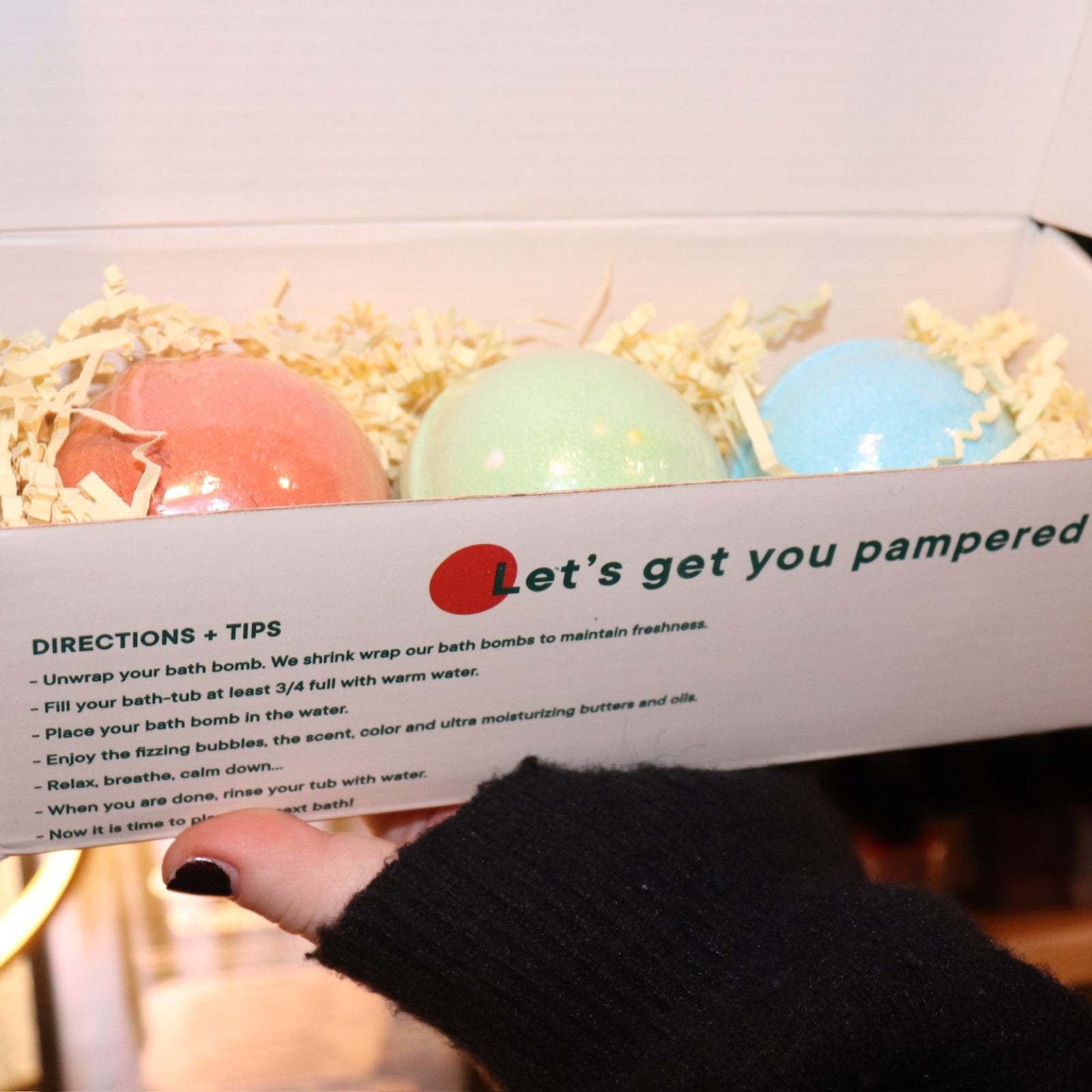 Someone holding the Holiday Christmas Bath Bomb Set in front of a colorful background, showing the inside.