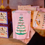Someone holding a Pink Christmas Tree Bath Soak in front of other bath holiday products.
