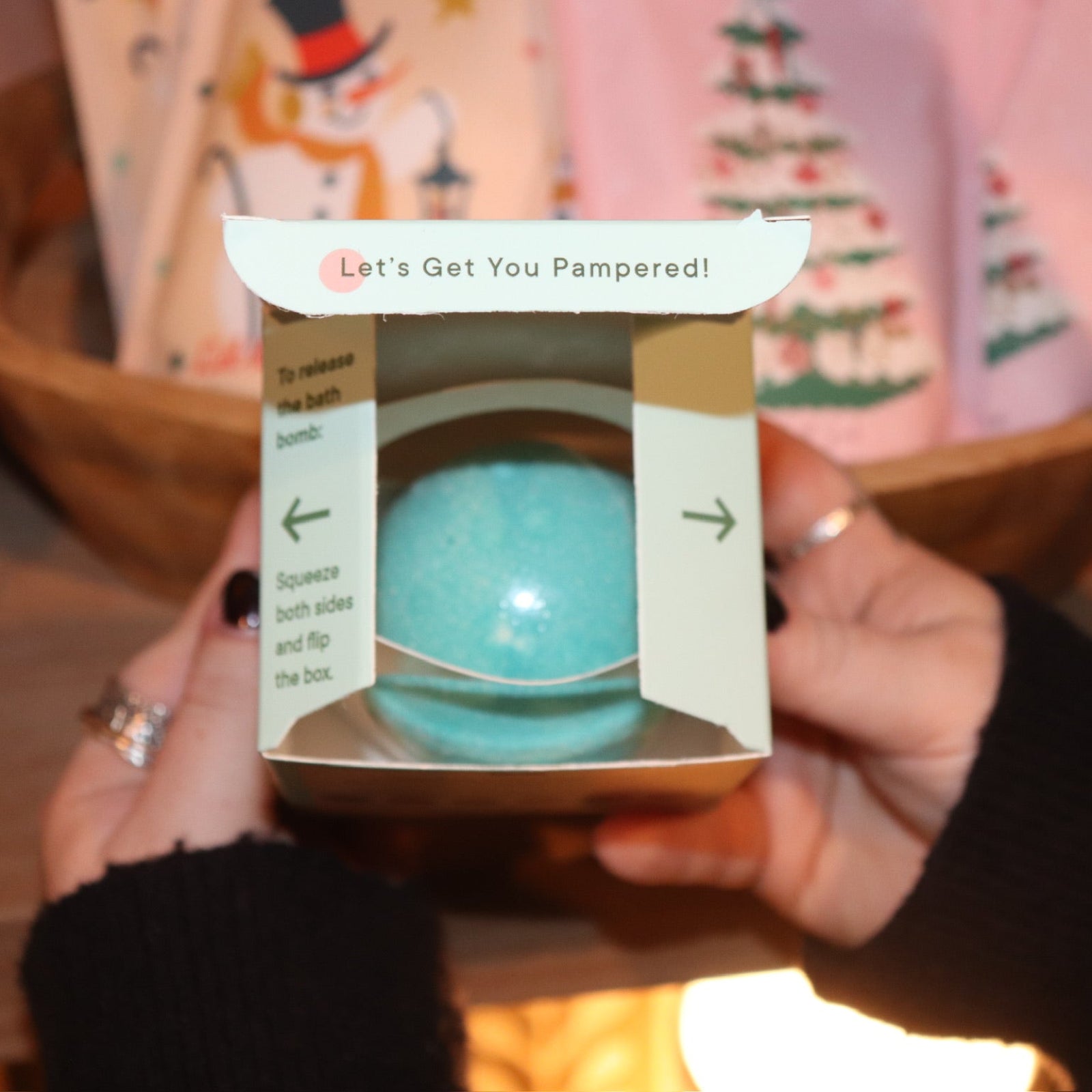 Someone holding the Nutcracker Bath Bomb in front of other holiday bath products, showing off the inside.