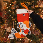 Someone holding the Felt Japanese Koi Fish Christmas Stocking in front of a Christmas tree.