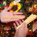 Someone holding the sticks from the Christmas Time Pick-up Sticks Conversation Game in front of a Christmas tree.