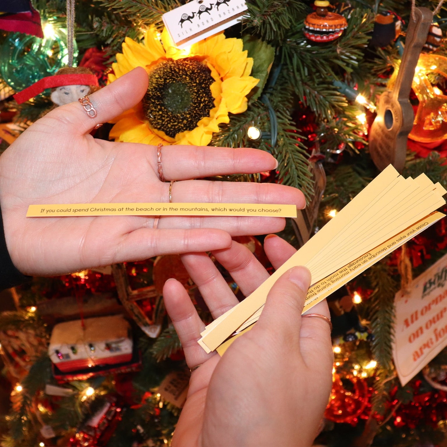 Someone holding the sticks from the Christmas Time Pick-up Sticks Conversation Game in front of a Christmas tree.