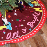An up-close image of the All Is Bright Embroidered Tree Skirt around the bottom of a tree.