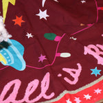 An up-close image of the All Is Bright Embroidered Tree Skirt around the bottom of a tree.