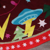 An up-close image of the All Is Bright Embroidered Tree Skirt around the bottom of a tree.