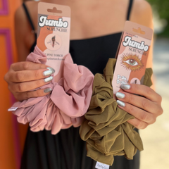 Someone holding the antique rose and olive colored XL Jumbo Chiffon Scrunchies in front of a pink and orange wall.