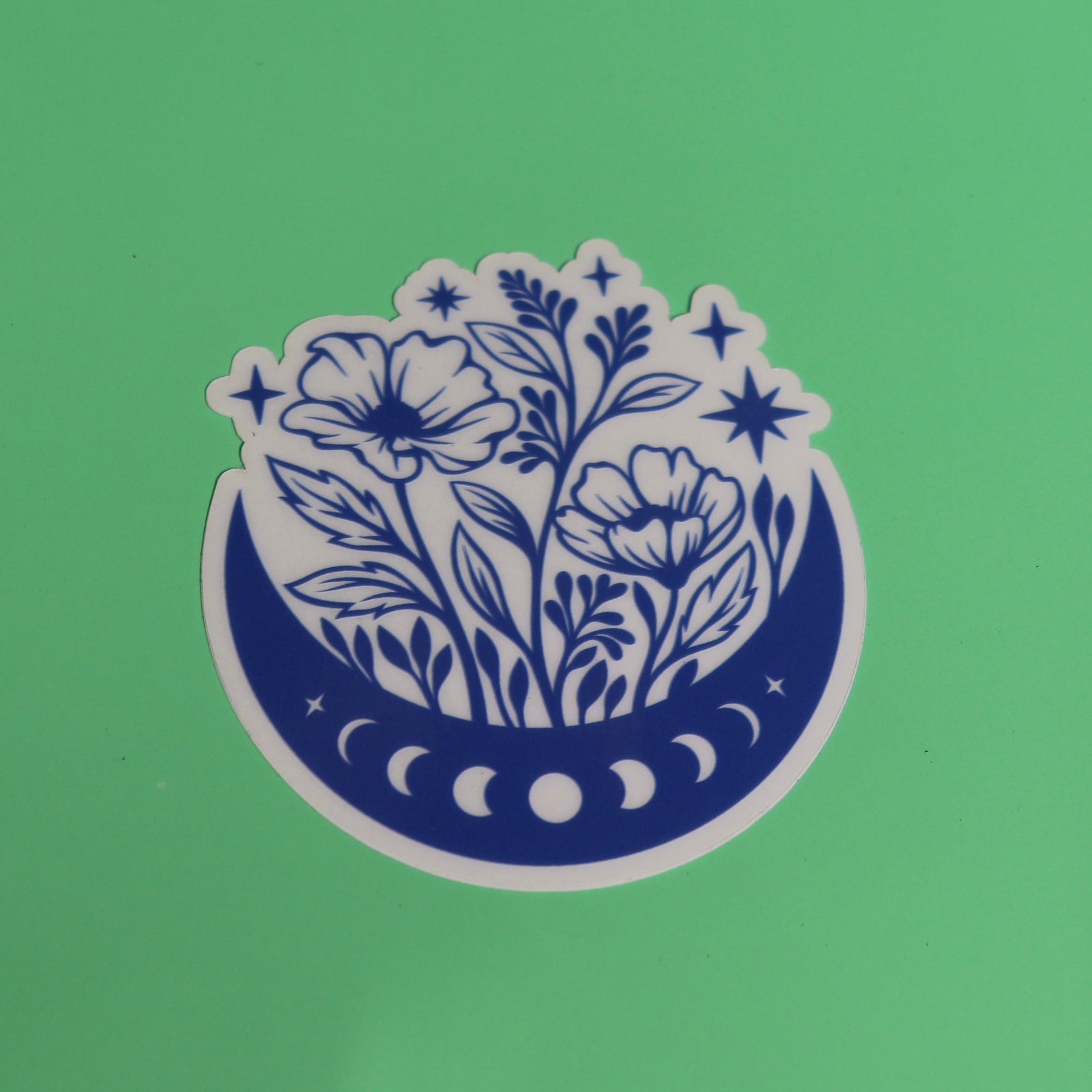 The Flower Moon Phase Sticker on a green background.
