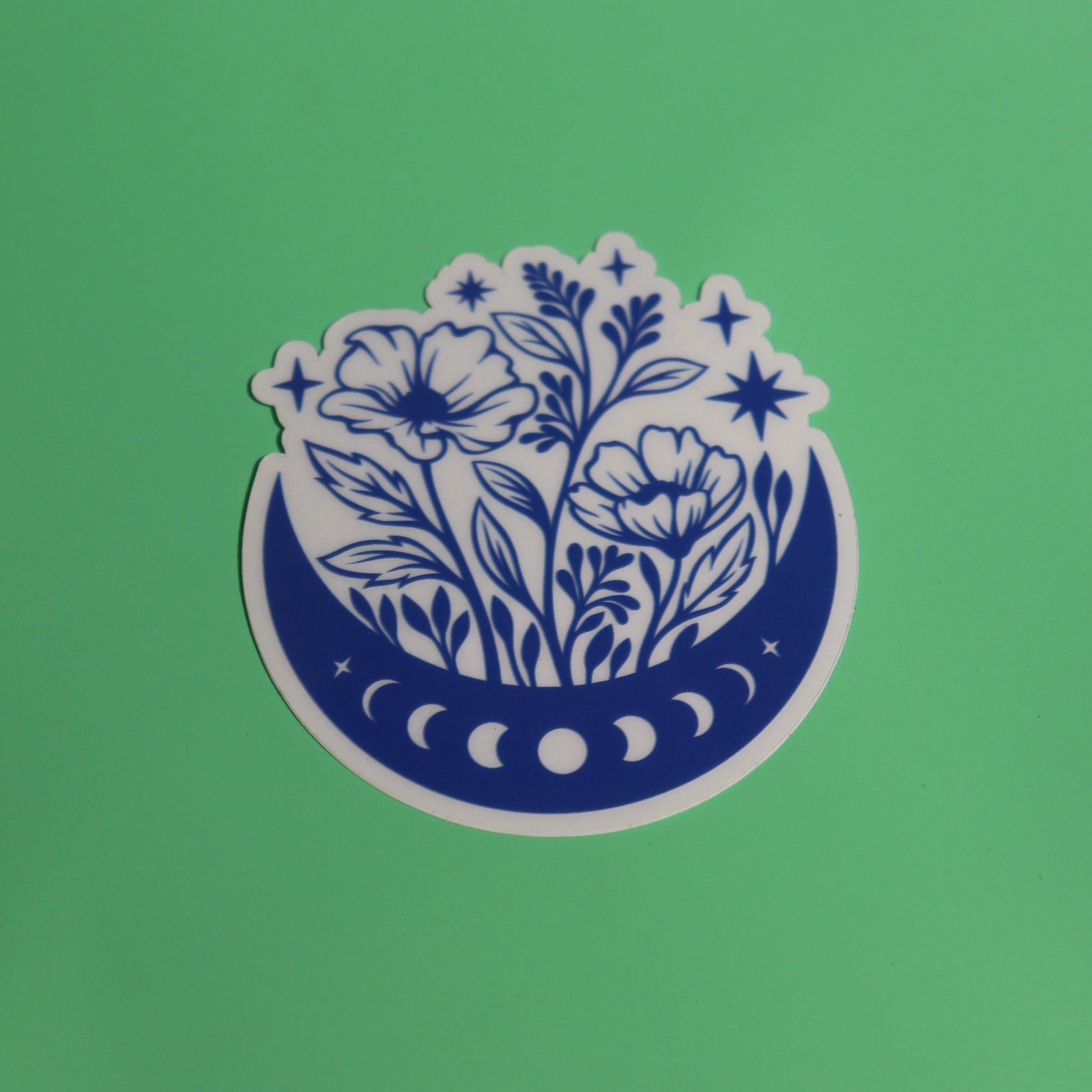 The Flower Moon Phase Sticker on a green background.