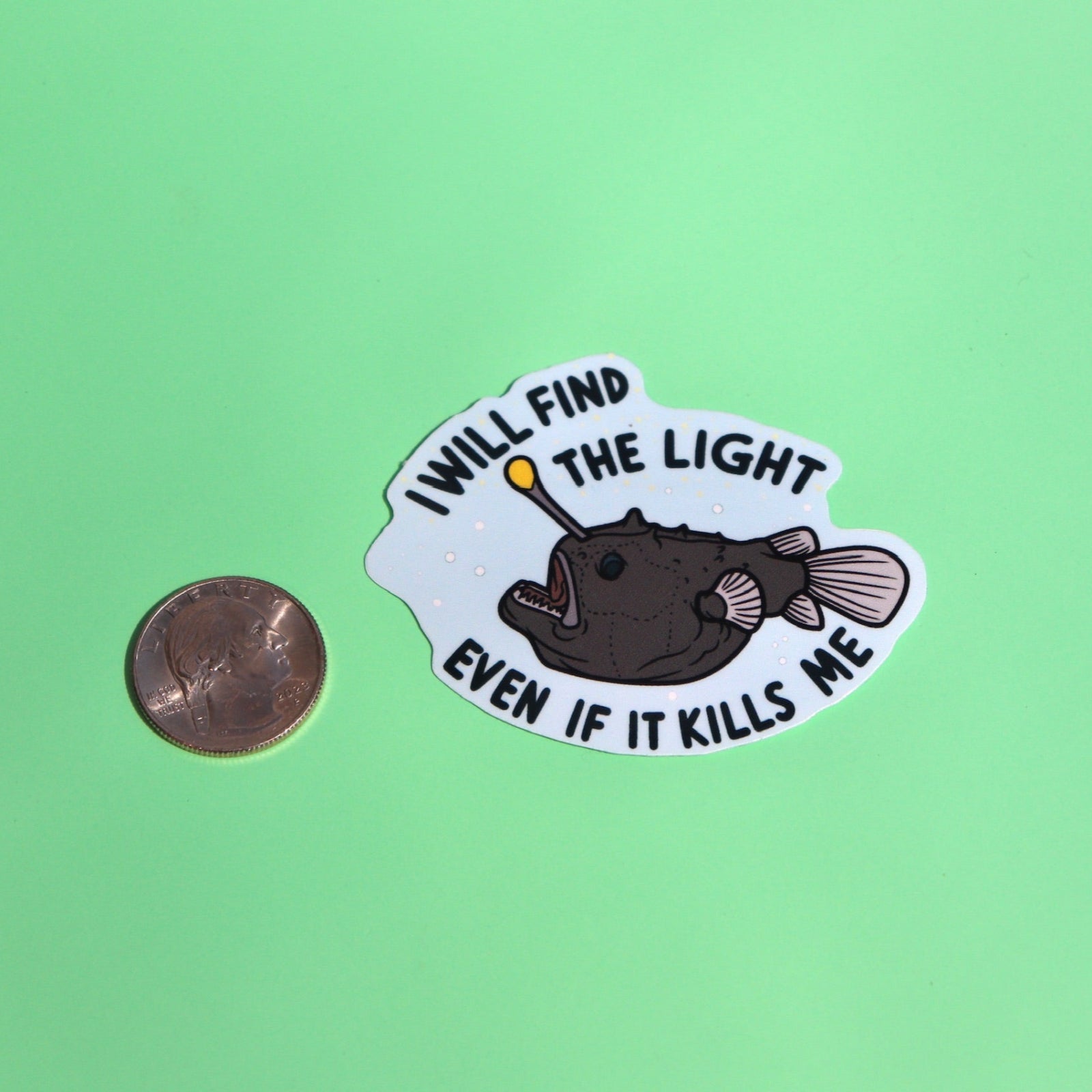 The Anglerfish Vinyl Sticker next to a quarter on a green background.