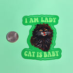 The I Am Lady Cat Is Baby 3 Inch Sticker next to a quarter on a green background.
