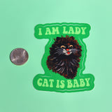 The I Am Lady Cat Is Baby 3 Inch Sticker next to a quarter on a green background.