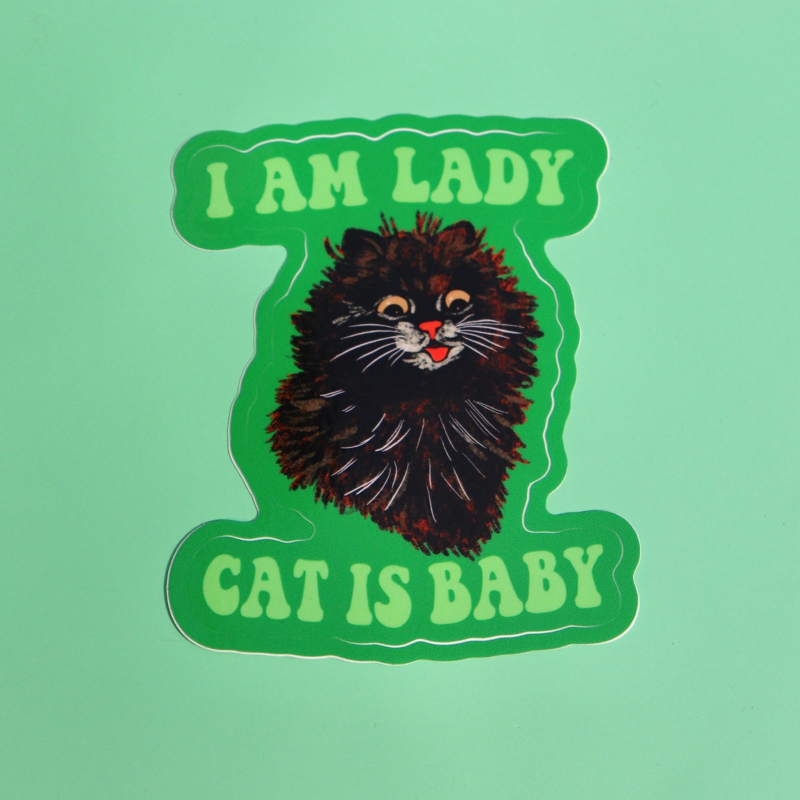 The I Am Lady Cat Is Baby 3 Inch Sticker on a green background.