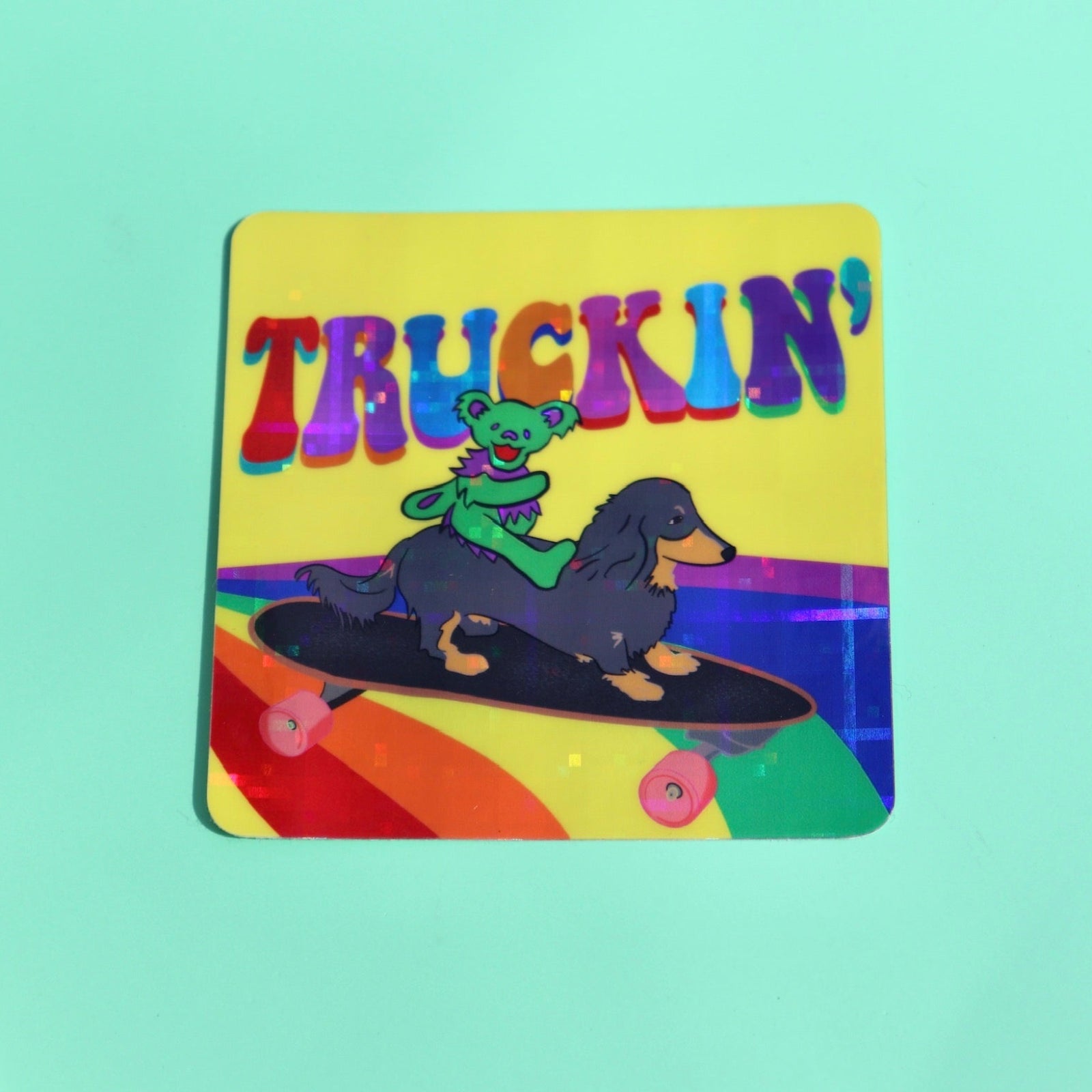 The Truckin Grateful Dead Sparkle 3 Inch Sticker on a green background.
