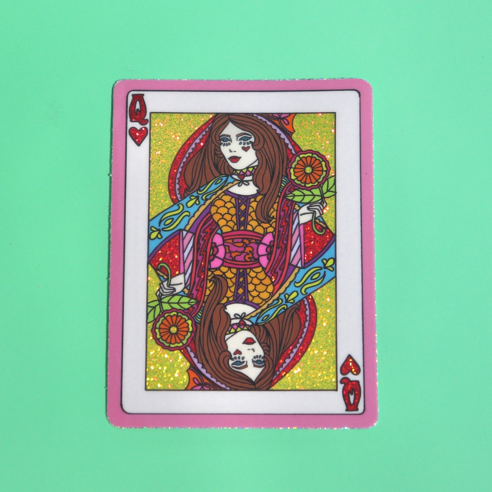 The Queen of Hearts Glitter 3 Inch Sticker on a green background.