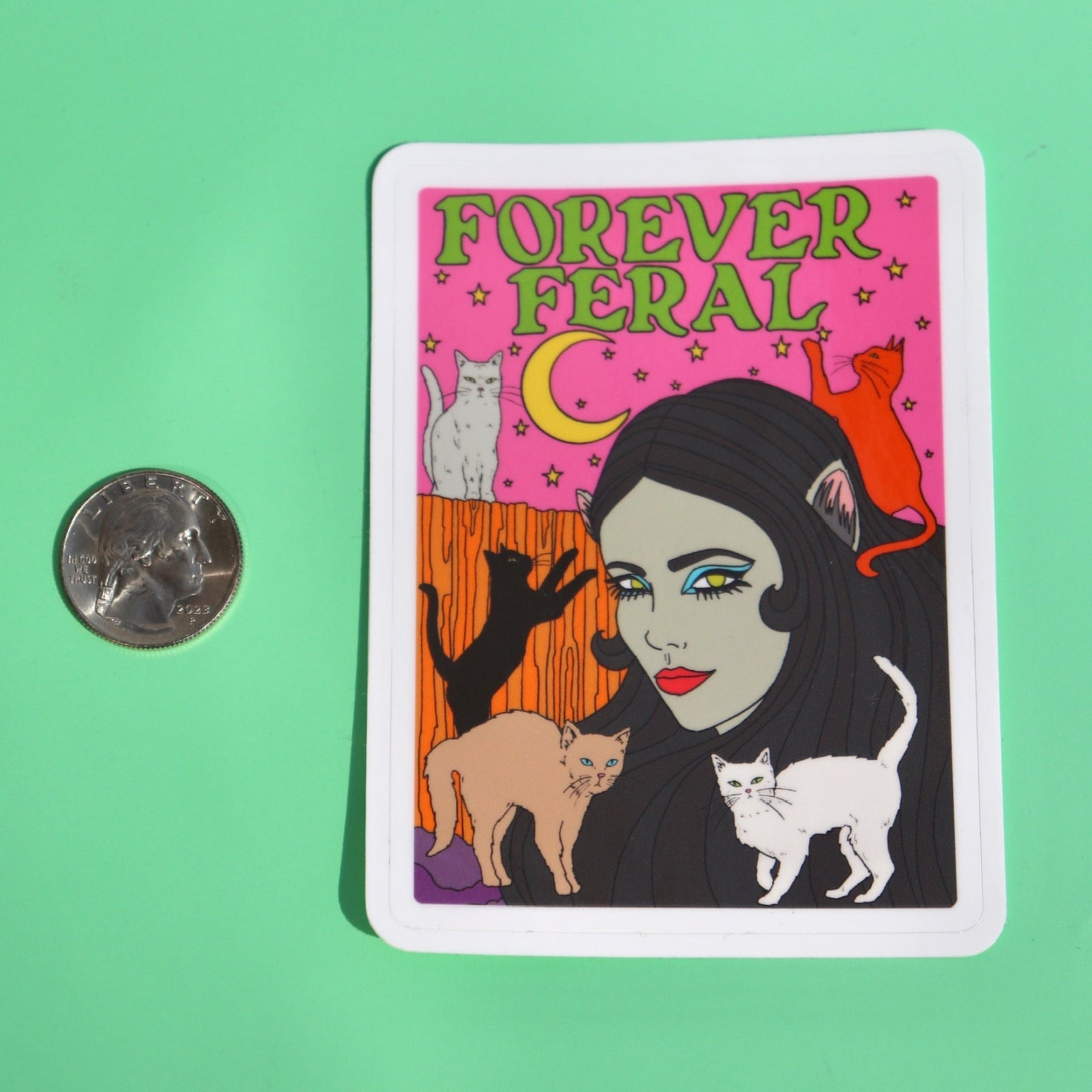 The Forever Feral 3 Inch Vinyl Sticker  next to a quarter on a green background.
