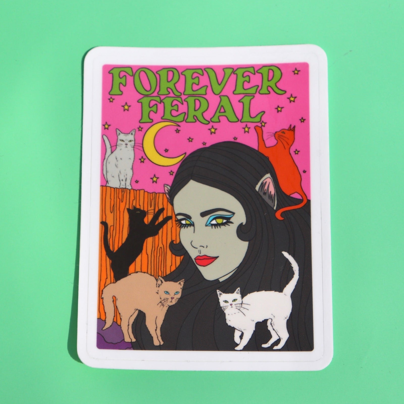 The Forever Feral 3 Inch Vinyl Sticker on a green background.