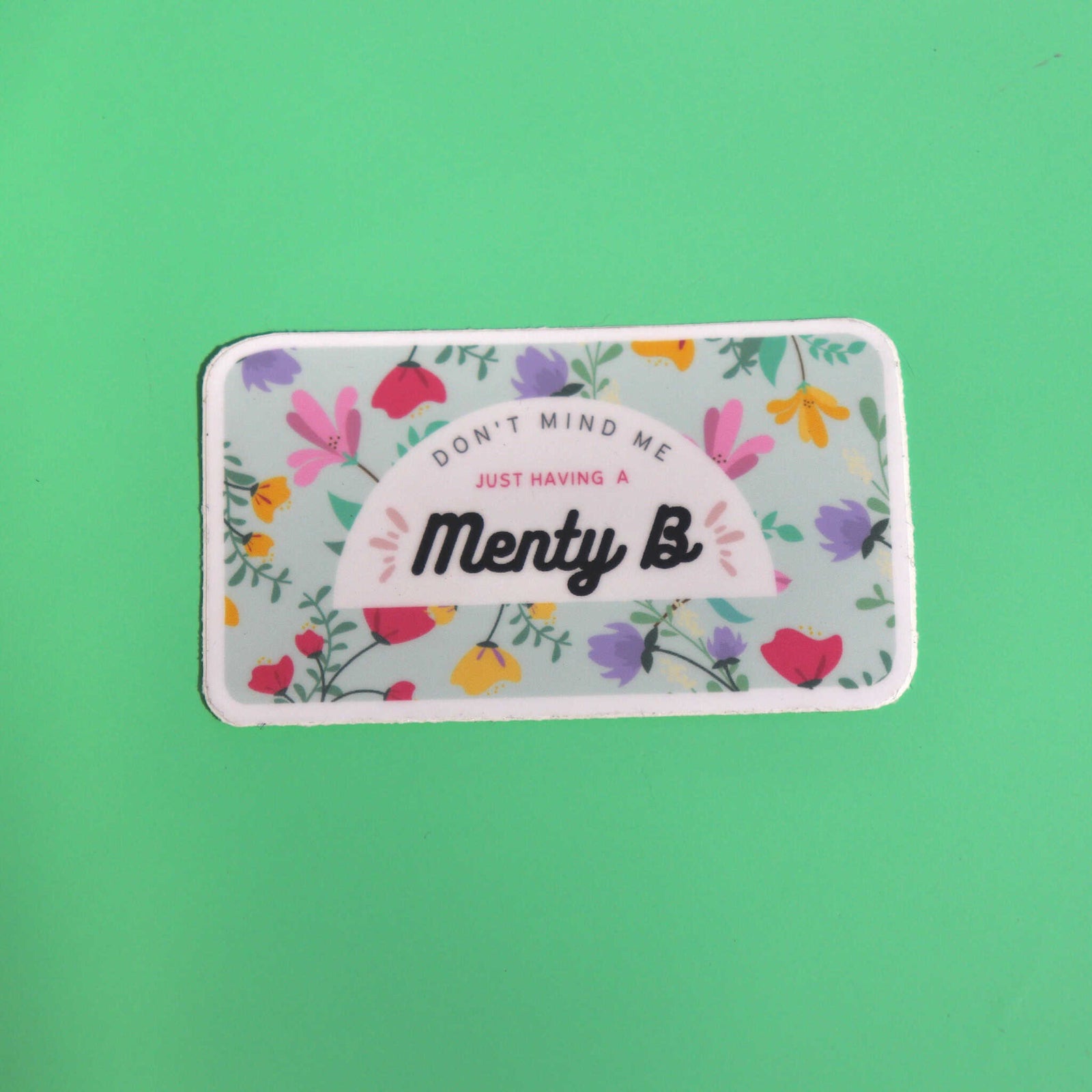 The Menty B Mental Health Anxiety Sticker on a green background.