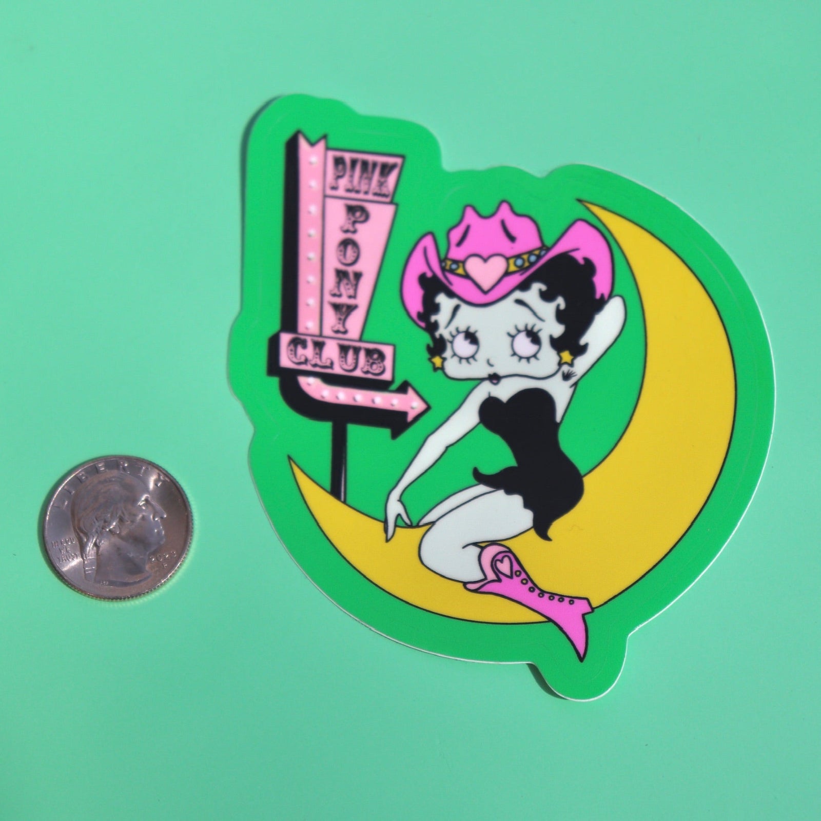 The Pink Pony Club Chappell Roan Sticker next to a quarter on a green background.