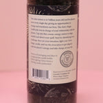 The back of the Astro Magic New Moon - Let it Grow Pillar Candle on a pink background.