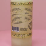 The back of the Affirmation Grief Candle - Pillar Candle with Cypress Blend on a pink background.
