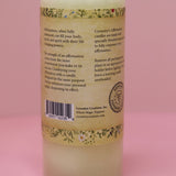The back of the Affirmation Grief Candle - Pillar Candle with Cypress Blend on a pink background.