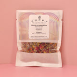 The Loving Flower Bath Salt Packet on a pink background.