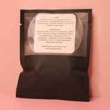 The back of the Soothing Flower Bath Salt Packet on a pink background.